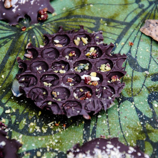 dark chocolate bite with bubble wrap texture and grinded nuts sprinkled over