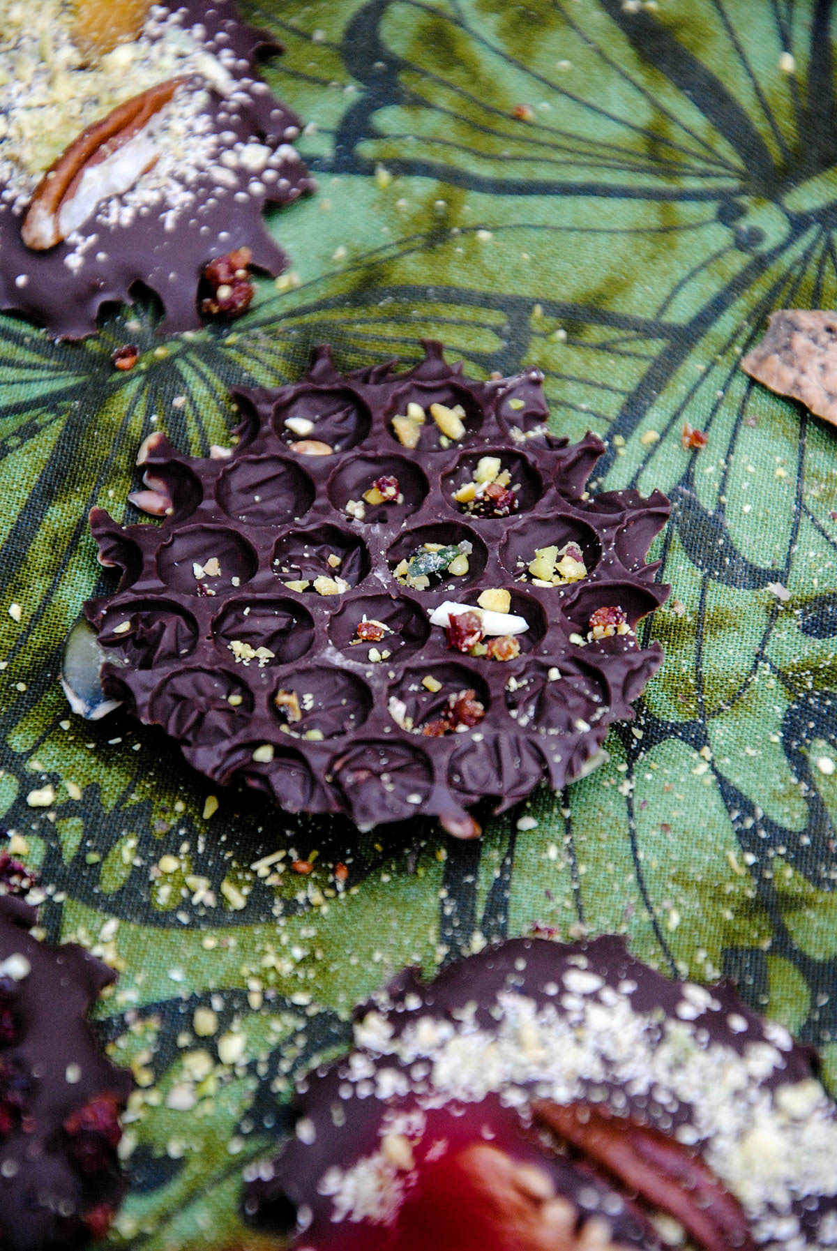 dark chocolate bite with bubble wrap texture and grinded nuts sprinkled over